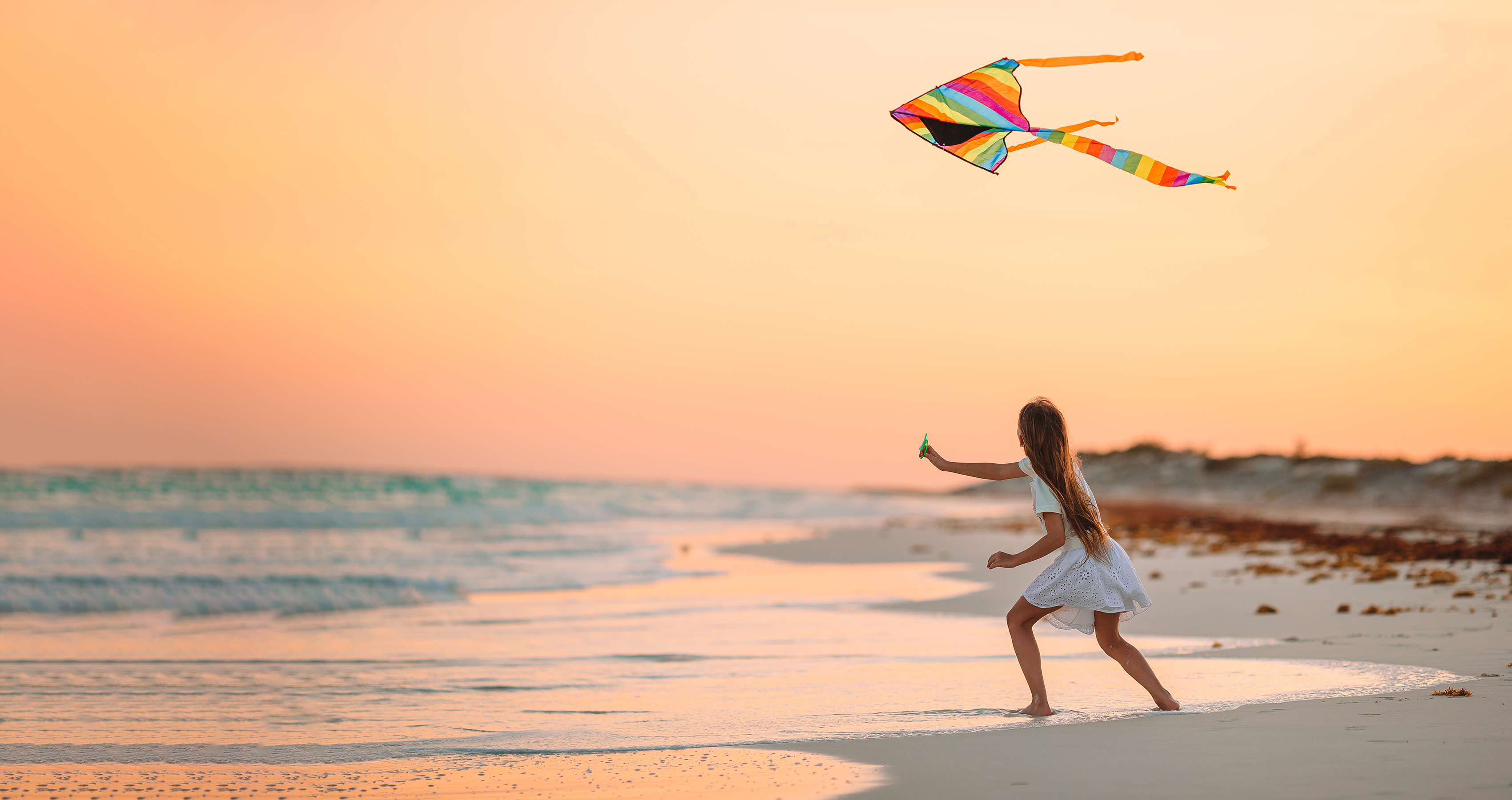 Girll on the beach flying a kite
